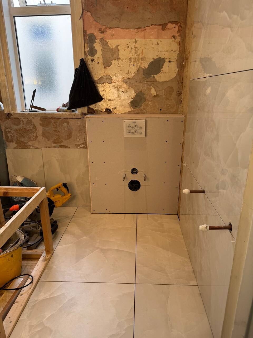 Bathroom mid-installation with pipework run and floor prepared for tiling