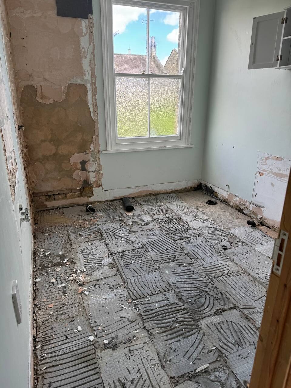 Period bathroom stripped to plaster with old floor tiles and adhesive lifted