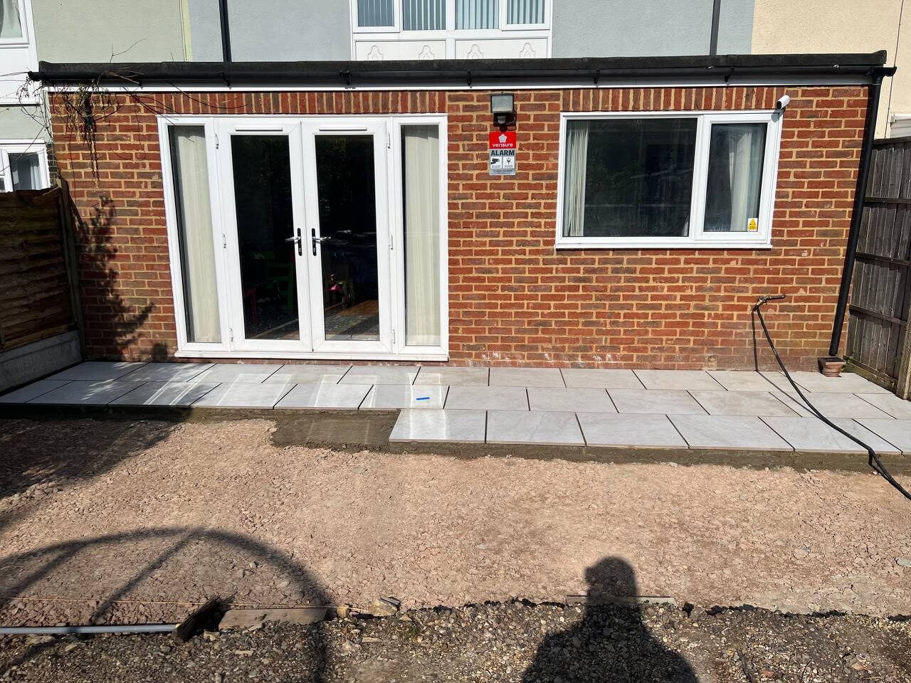 Patio slabs part-laid across the full width of the house