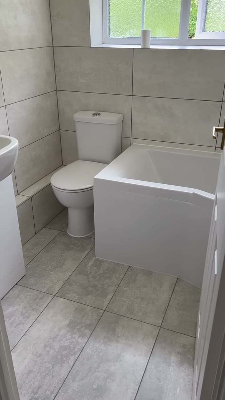 Finished bathroom in grey stone-effect tiles with shower bath, WC and vanity basin