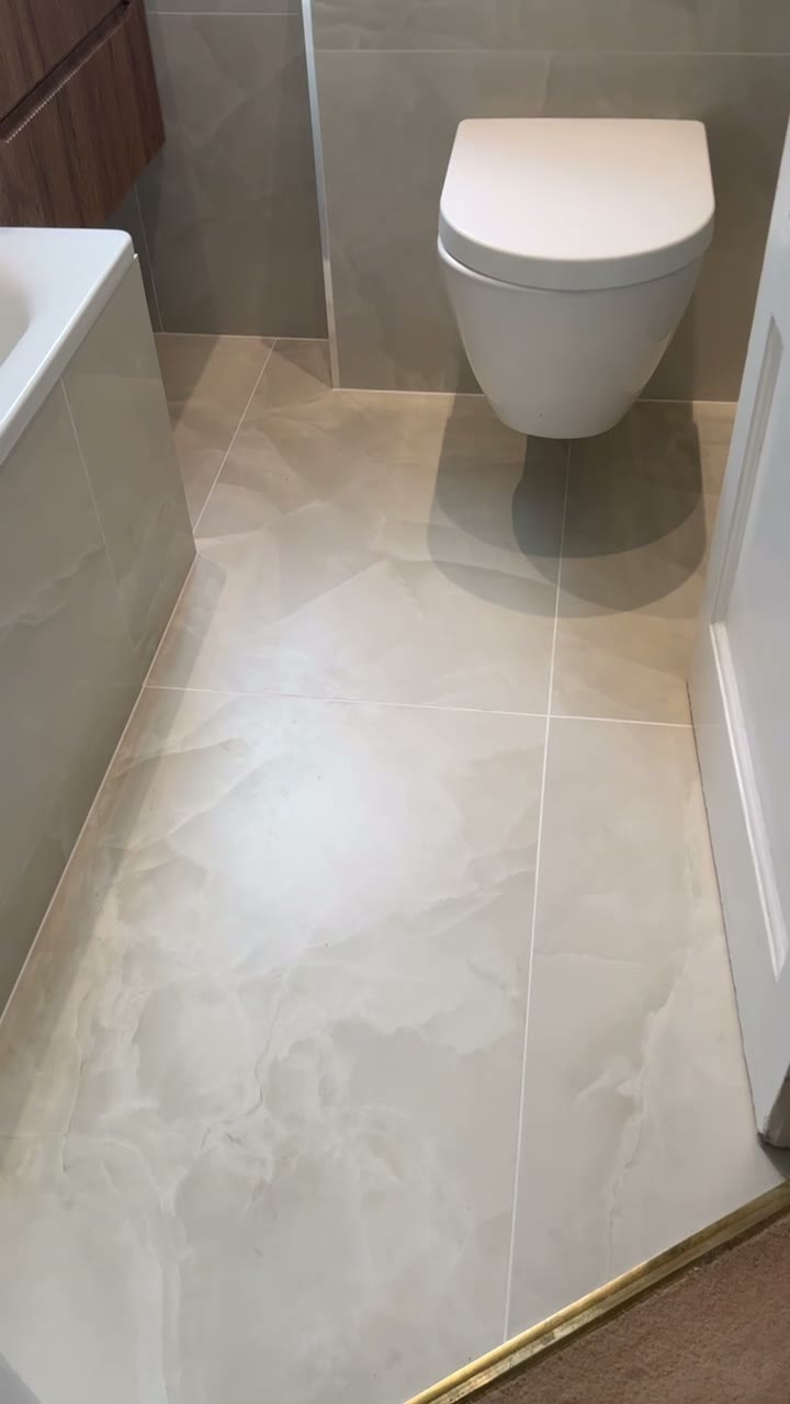 Finished cream marble-effect bathroom with wall-hung WC and walnut vanity