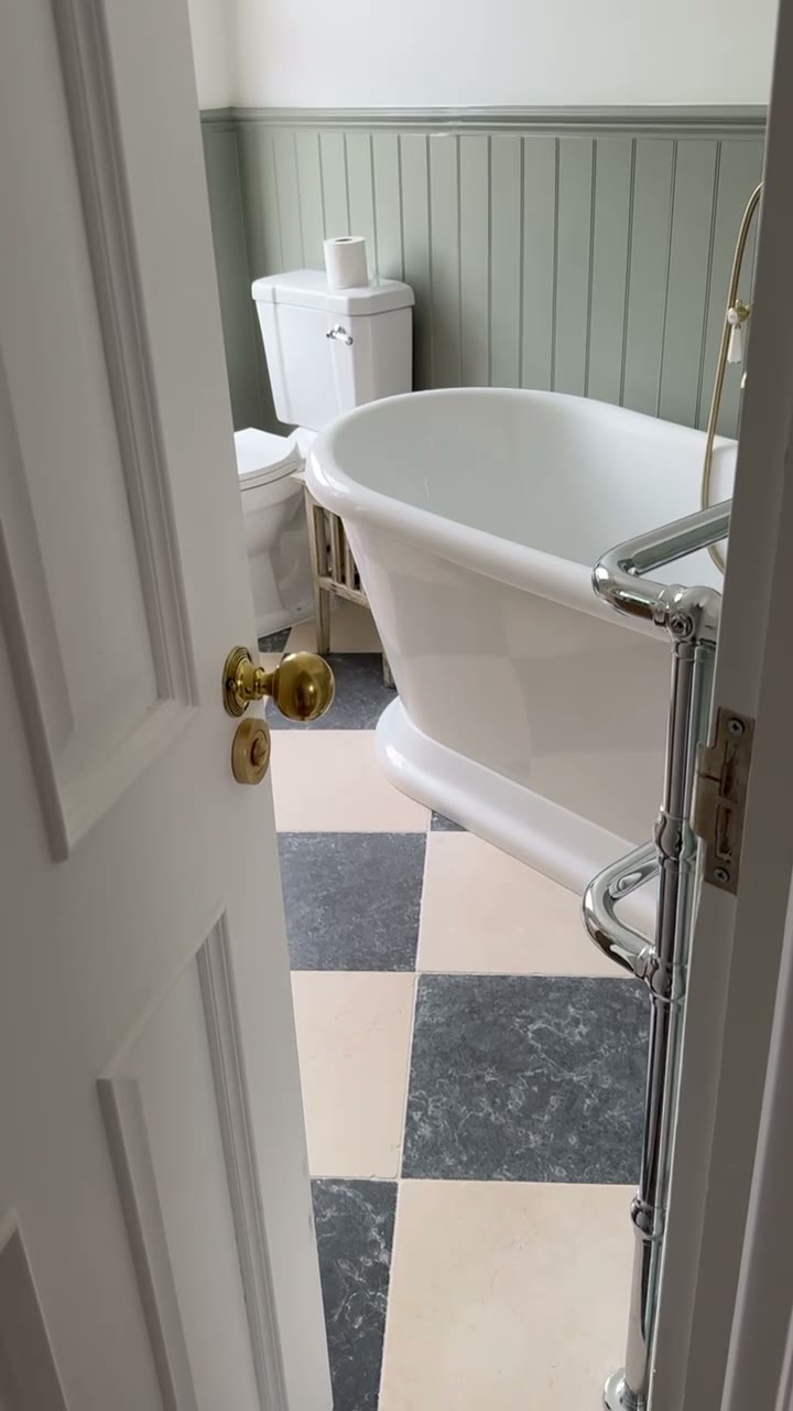 Victorian-style bathroom with sage panelling, roll-top bath and chequerboard marble floor