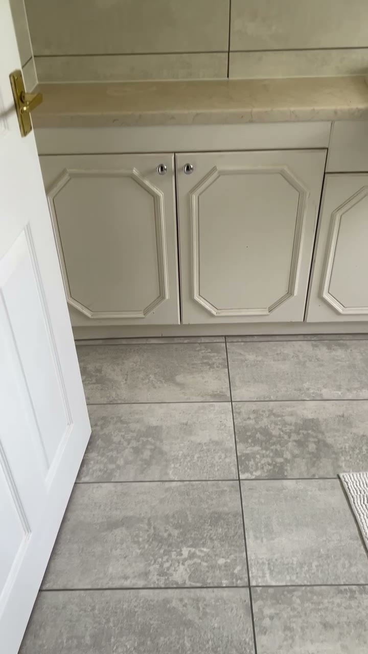 Fitted cream panelled units with stone worktop over stone-effect floor tiles