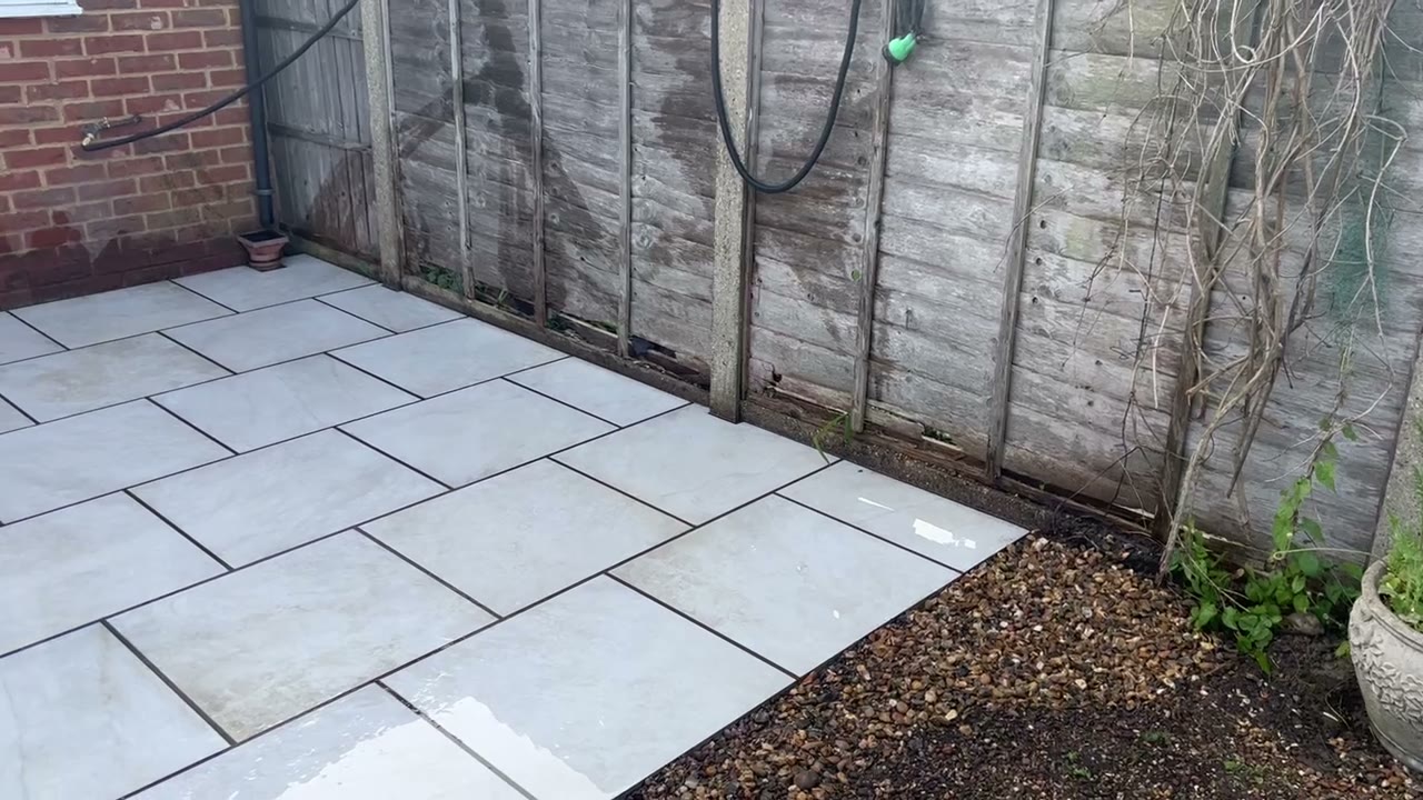 Finished grey porcelain patio with dark pointing and a gravel border